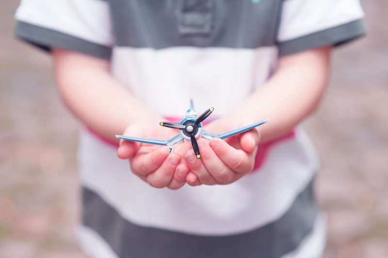 Little boy cupping a toy airplane in his hands